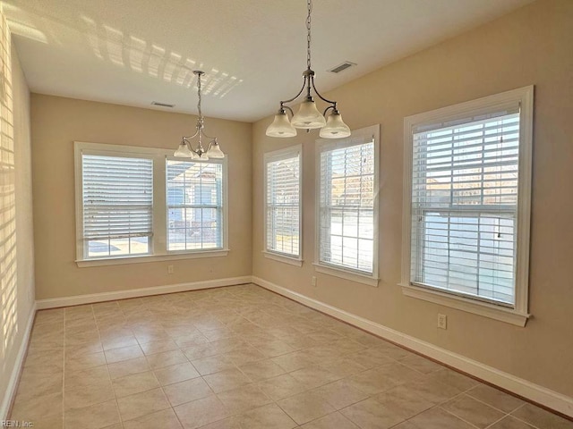 unfurnished dining area featuring plenty of natural light, a chandelier, and light tile patterned floors