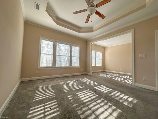 spare room with ceiling fan, dark carpet, a tray ceiling, and crown molding