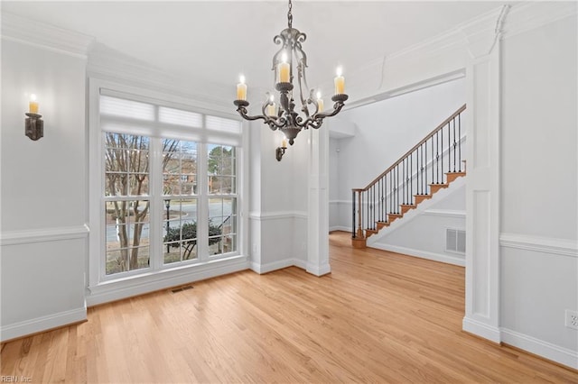 unfurnished dining area featuring a chandelier, plenty of natural light, hardwood / wood-style flooring, and ornamental molding