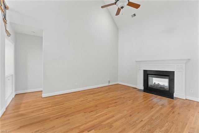 unfurnished living room with a multi sided fireplace, light hardwood / wood-style flooring, high vaulted ceiling, and ceiling fan