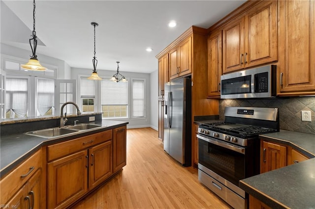 kitchen featuring tasteful backsplash, sink, light hardwood / wood-style flooring, pendant lighting, and stainless steel appliances