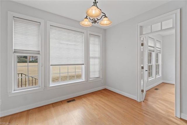 unfurnished dining area featuring light hardwood / wood-style floors and a chandelier