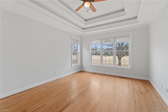 empty room featuring ornamental molding, ceiling fan, a raised ceiling, and light hardwood / wood-style flooring