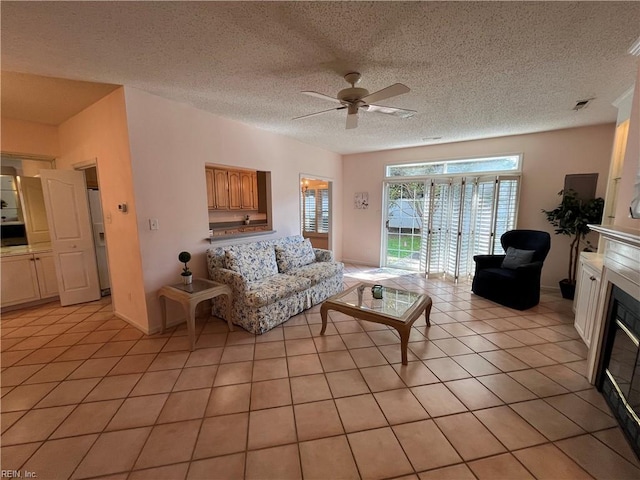 living room featuring ceiling fan, a textured ceiling, and light tile patterned floors