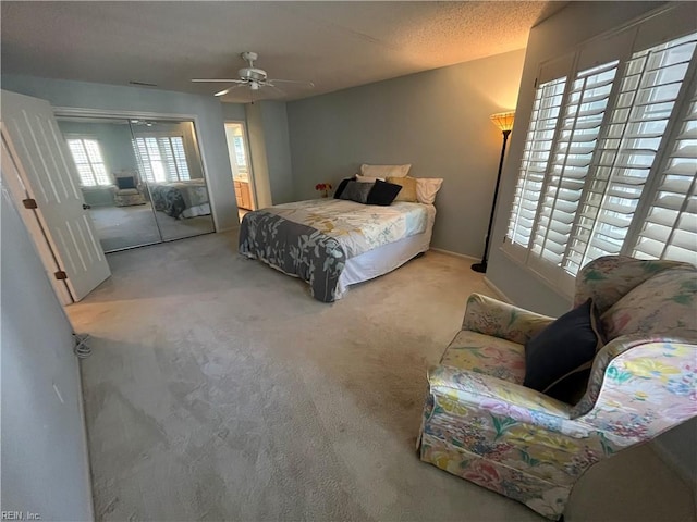 bedroom with ceiling fan, a closet, light carpet, and a textured ceiling