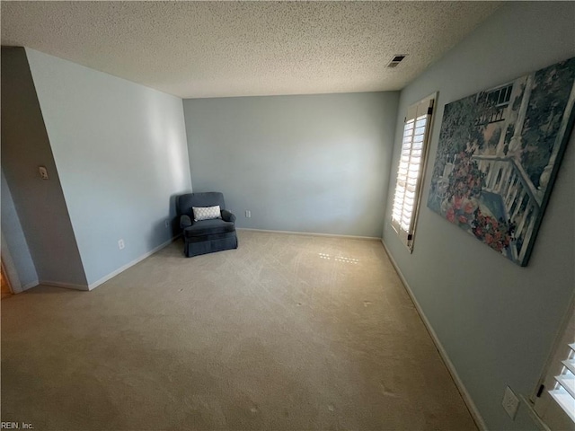 unfurnished room with light colored carpet and a textured ceiling