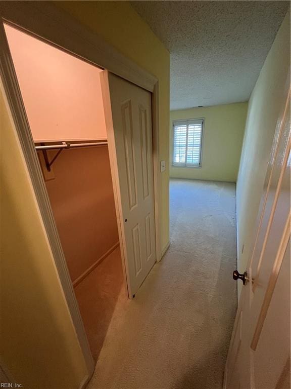 hall featuring light carpet and a textured ceiling