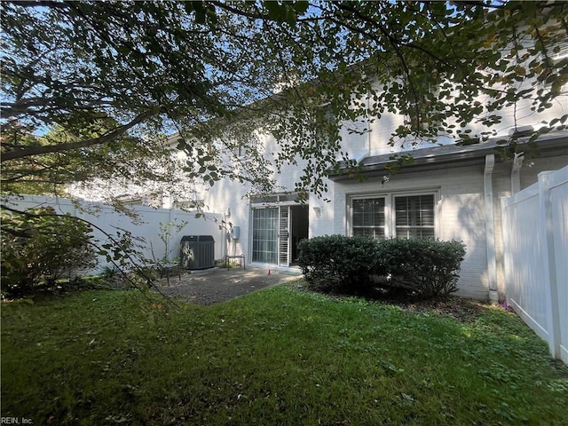 rear view of house with a yard, cooling unit, and a patio area