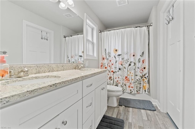 bathroom featuring vanity, hardwood / wood-style flooring, a shower with curtain, and toilet