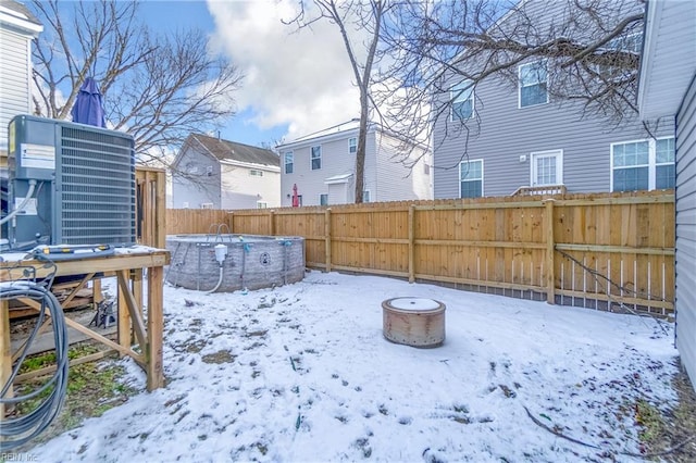 snowy yard featuring cooling unit and an outdoor fire pit