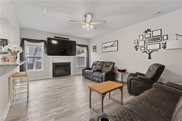 living room featuring ceiling fan, light wood-type flooring, and a wealth of natural light