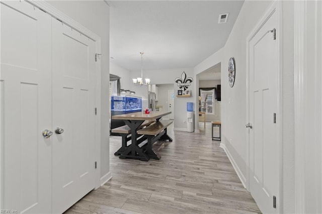 hallway featuring an inviting chandelier and light hardwood / wood-style floors