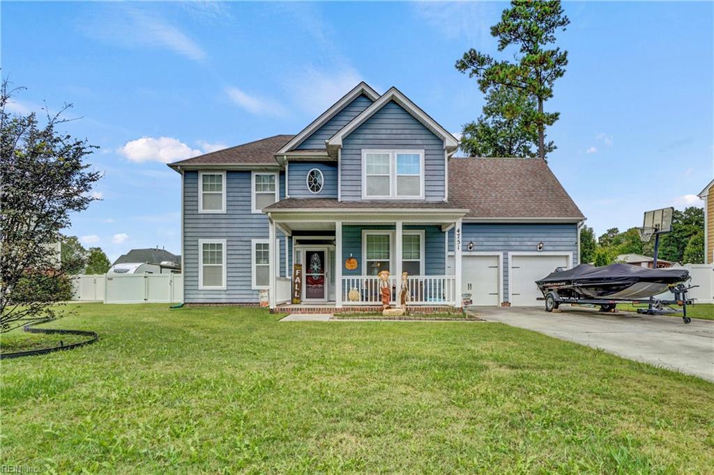 view of front of house featuring a garage, covered porch, and a front lawn