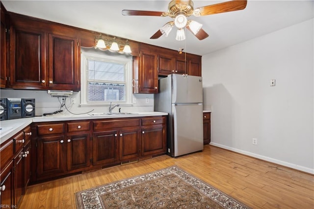 kitchen featuring ceiling fan, sink, stainless steel refrigerator, and light hardwood / wood-style flooring