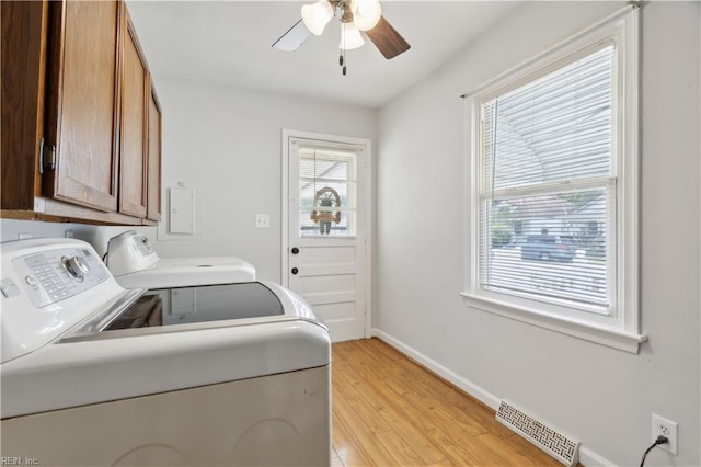 clothes washing area with washing machine and dryer, cabinets, ceiling fan, and light wood-type flooring