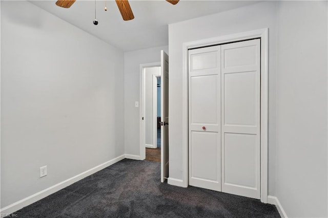 unfurnished bedroom featuring ceiling fan, a closet, and dark colored carpet