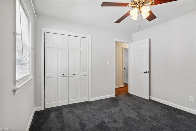 unfurnished bedroom with dark carpet, ceiling fan, and a closet