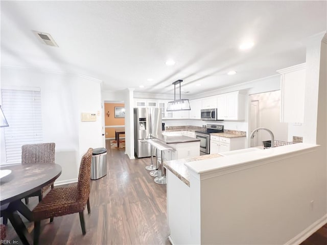 kitchen with hanging light fixtures, stainless steel appliances, kitchen peninsula, and white cabinets