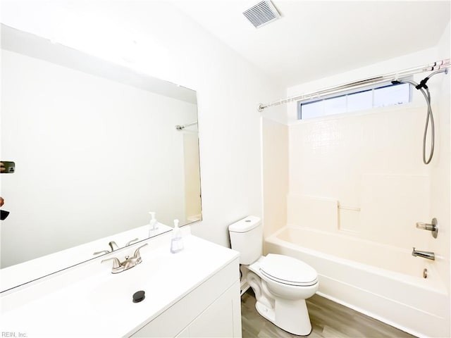 full bathroom featuring hardwood / wood-style flooring, washtub / shower combination, vanity, and toilet