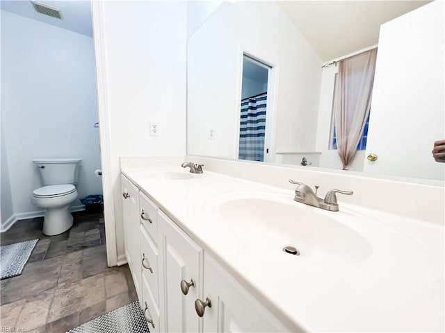 bathroom with lofted ceiling, vanity, and toilet