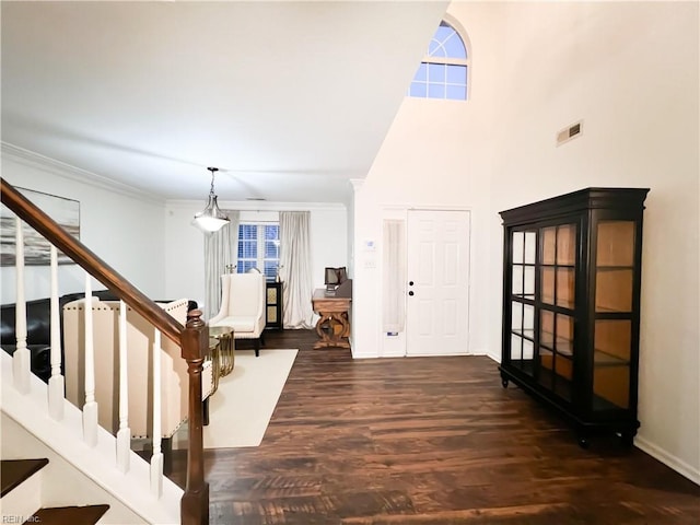 entryway with a high ceiling, crown molding, and dark hardwood / wood-style flooring