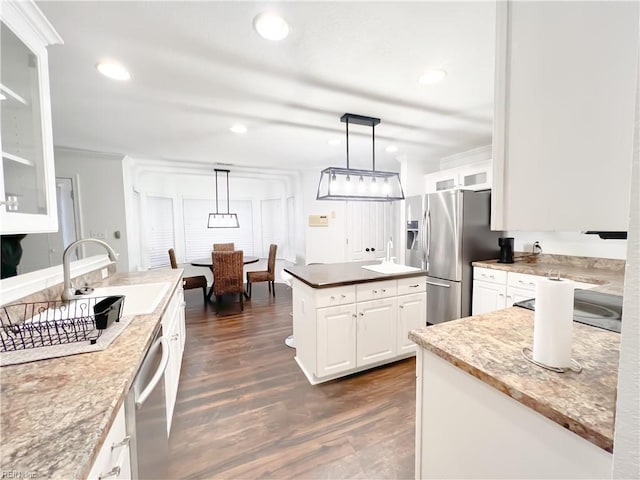 kitchen with appliances with stainless steel finishes, dark hardwood / wood-style flooring, pendant lighting, light stone countertops, and white cabinets