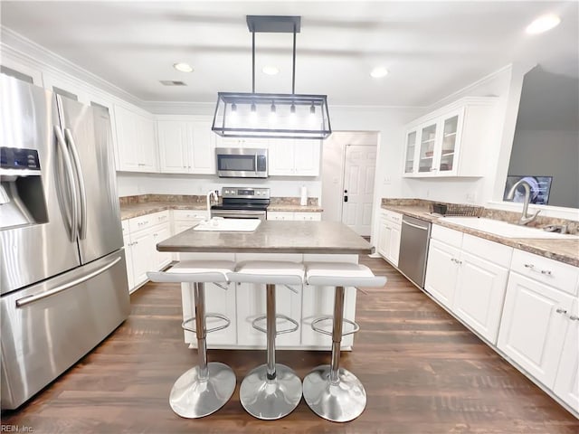 kitchen with pendant lighting, sink, appliances with stainless steel finishes, white cabinetry, and light stone countertops