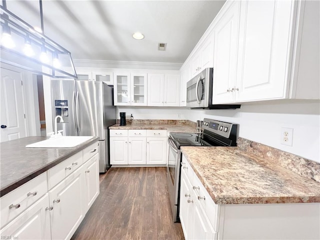 kitchen with appliances with stainless steel finishes, white cabinetry, sink, hanging light fixtures, and dark wood-type flooring