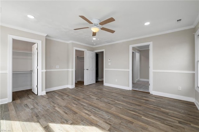 unfurnished bedroom with ceiling fan, ornamental molding, dark hardwood / wood-style flooring, and two closets