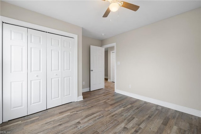 unfurnished bedroom featuring hardwood / wood-style flooring, ceiling fan, and a closet