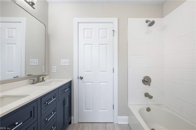 bathroom with hardwood / wood-style flooring, vanity, and tiled shower / bath combo