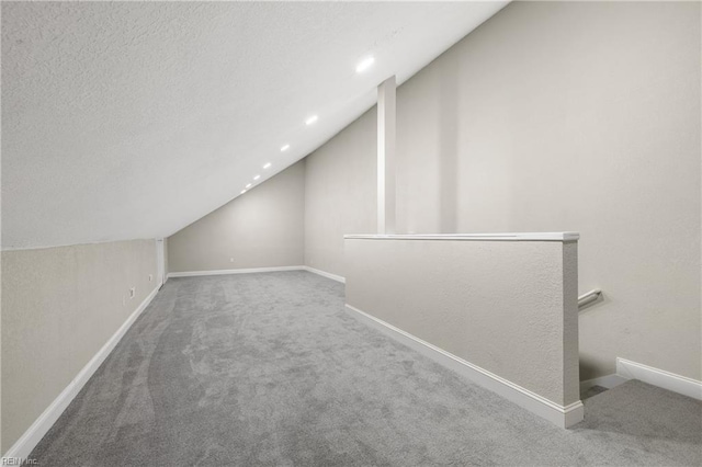 bonus room with vaulted ceiling, a textured ceiling, and carpet