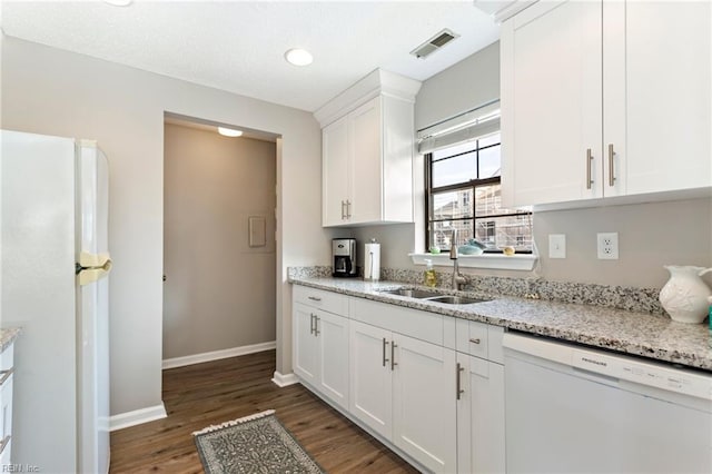 kitchen featuring sink, dark hardwood / wood-style floors, white appliances, light stone countertops, and white cabinets