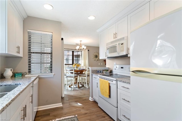 kitchen with white appliances, dark wood-type flooring, white cabinetry, light stone counters, and decorative light fixtures