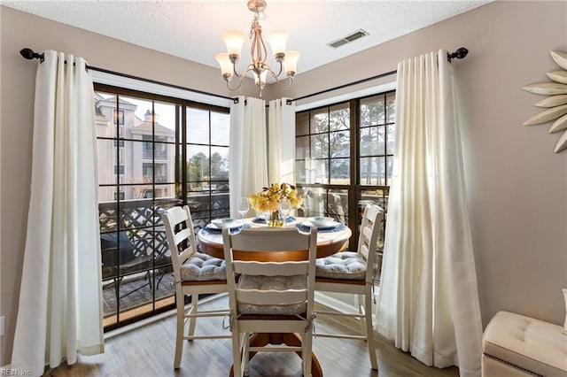 dining space featuring a notable chandelier, a textured ceiling, and light wood-type flooring