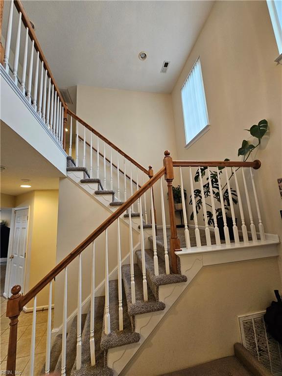 stairway with tile patterned flooring and a high ceiling