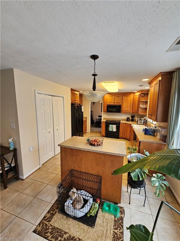 kitchen featuring pendant lighting, light tile patterned floors, sink, black appliances, and a textured ceiling