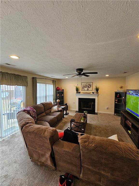 living room with ceiling fan, carpet floors, and a textured ceiling