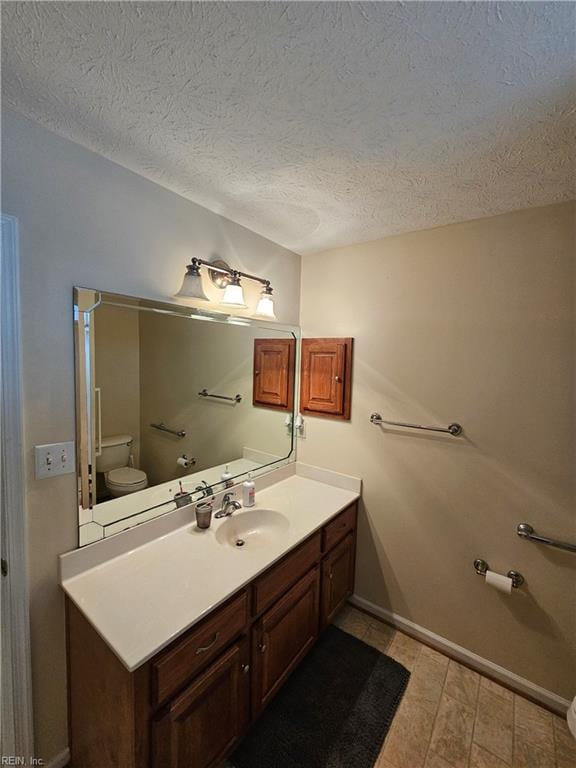 bathroom with vanity, toilet, and a textured ceiling