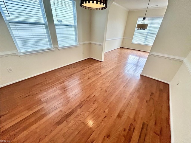 interior space with a healthy amount of sunlight, crown molding, and hardwood / wood-style floors