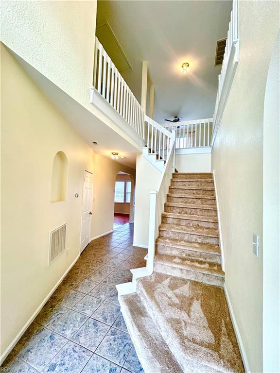 stairway with tile patterned floors and a towering ceiling