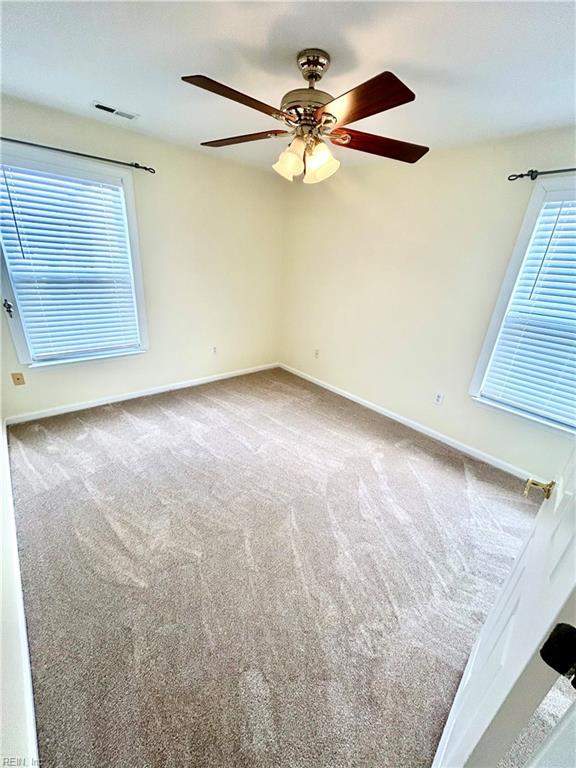 unfurnished room with ceiling fan, plenty of natural light, and carpet flooring