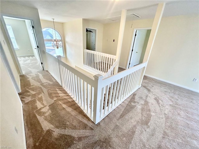 corridor with an inviting chandelier and carpet floors