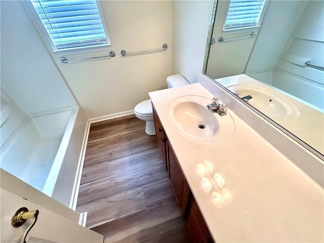 bathroom featuring wood-type flooring, toilet, a wealth of natural light, and vanity