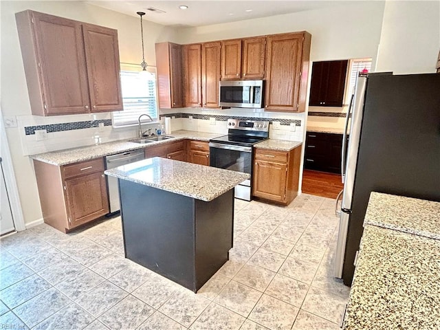 kitchen featuring a center island, stainless steel appliances, sink, hanging light fixtures, and backsplash