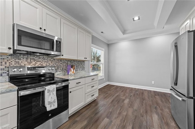 kitchen with a raised ceiling, appliances with stainless steel finishes, backsplash, white cabinets, and light stone countertops