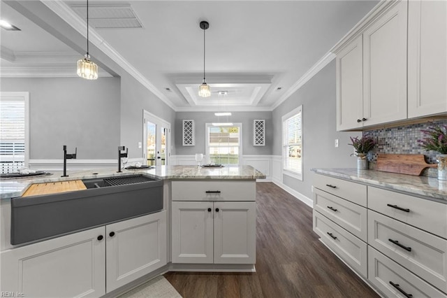 kitchen featuring light stone counters, pendant lighting, white cabinets, and crown molding