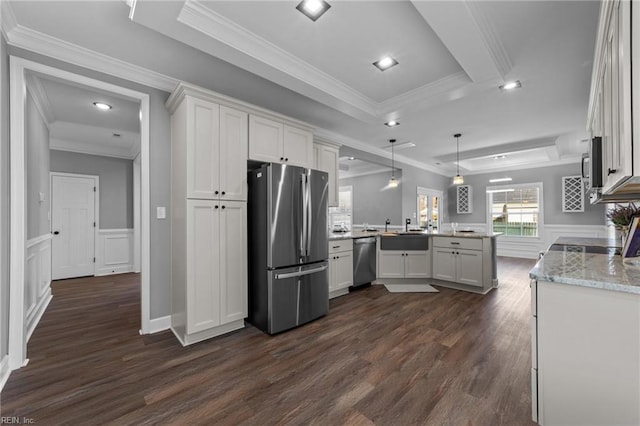 kitchen with kitchen peninsula, hanging light fixtures, appliances with stainless steel finishes, white cabinets, and a tray ceiling