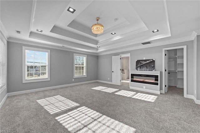 unfurnished living room featuring a tray ceiling, ornamental molding, and carpet flooring