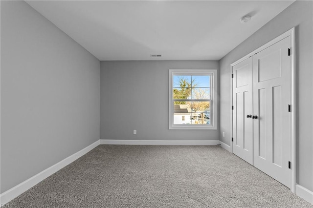 unfurnished bedroom with a closet and light colored carpet